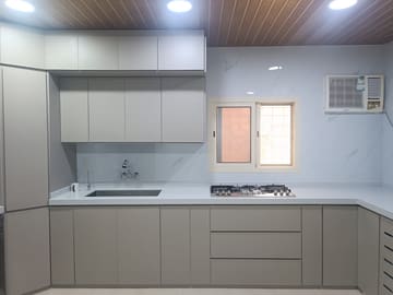 مطبخ بجدار مكسو ببديل الرخام الأبيض خلف سطح العمل